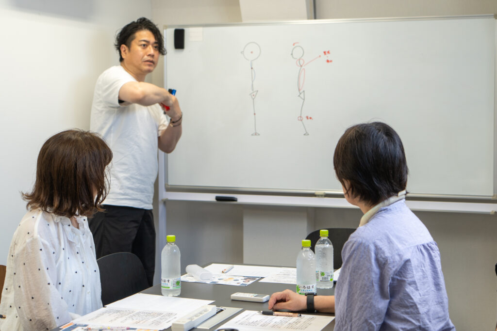 ホワイトボードで図解しながら日本人の骨格と反り腰のメカニズムを解説する講師