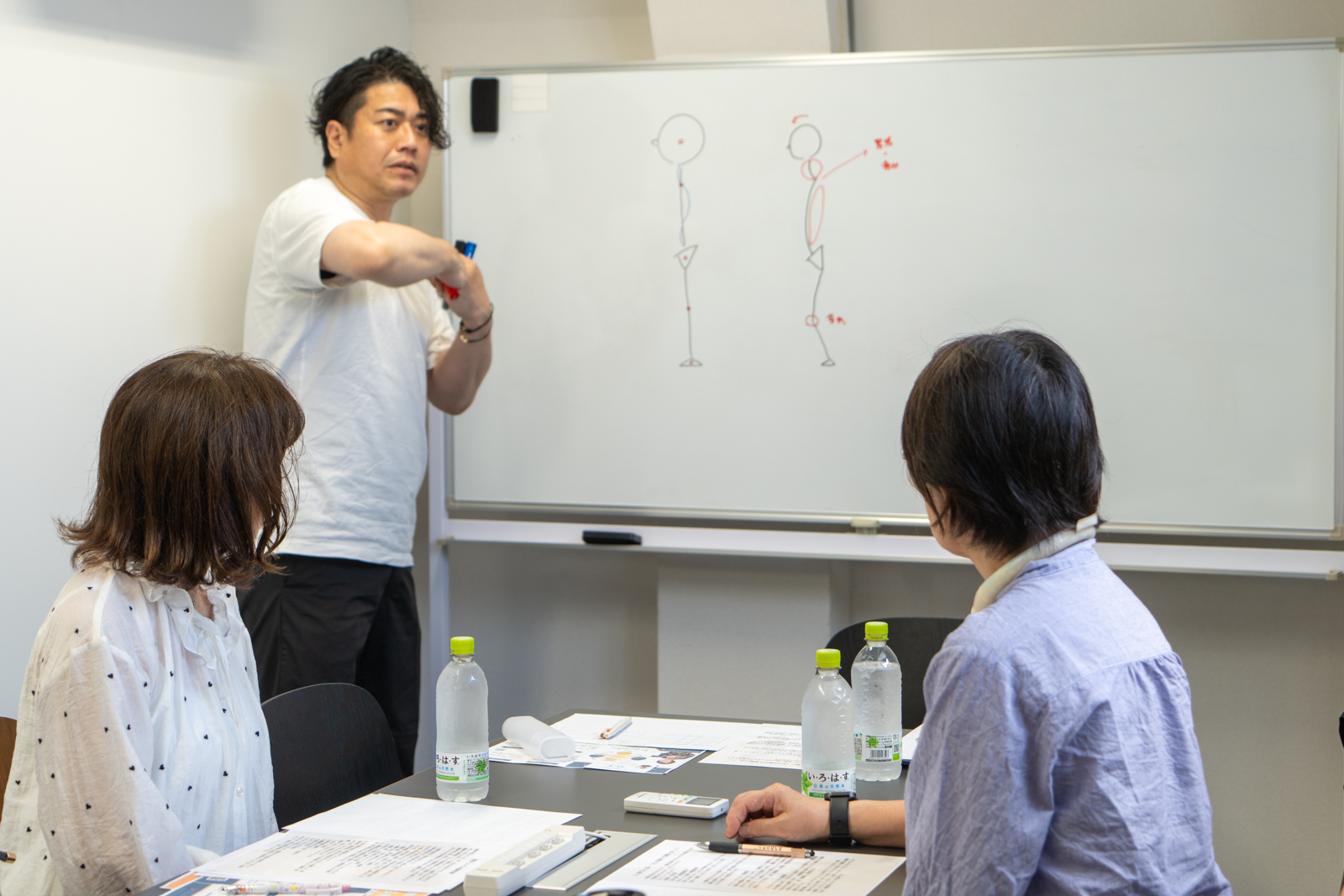 ホワイトボードで図解しながら日本人の骨格と反り腰のメカニズムを解説する講師