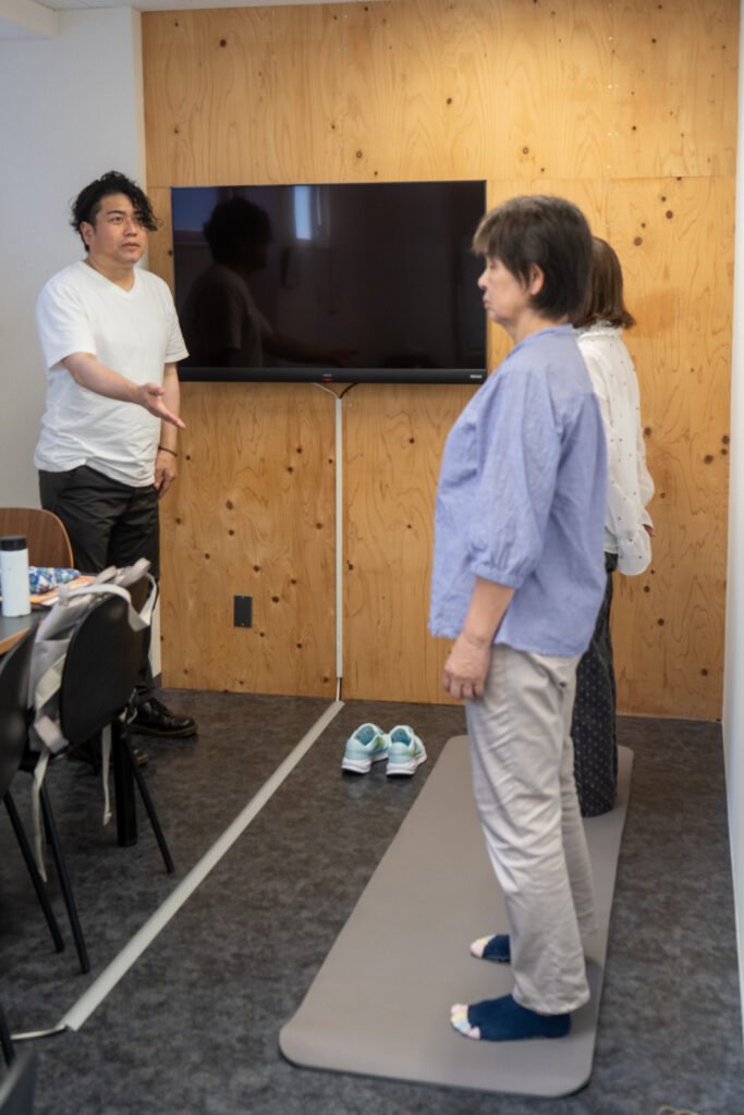 マットの上に立ち、筋肉の正しい使い方とS字カーブを保つ立ち方を学ぶ受講者たち
